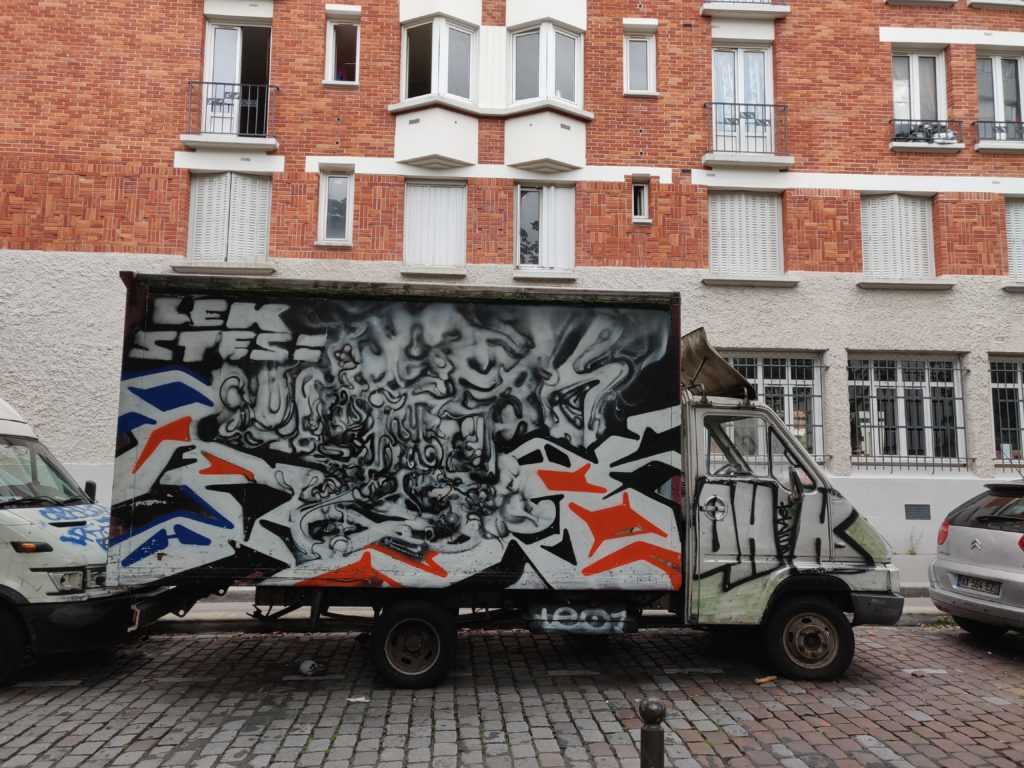 Graffiti auf Lastwägen werden nicht nur alleine darauf angebracht. Im Bild ein von STESI als organischer, bzw. biomechanischer Stil beschriebene Gestaltung eines Lastwagens in Zusammenarbeit mit LEK_75019. Hier trifft ein abstrakter Stil mit verschwindenden Linien auf einen eckigen Stil mit klaren Abgrenzungen.